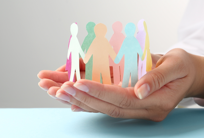 A woman's hands cupped together holding a circle of paper dolls holding hands