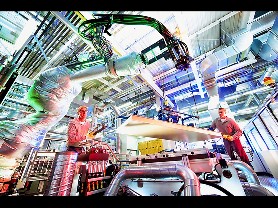 Employees in a factory using machines and working together to assemble insulation panels.