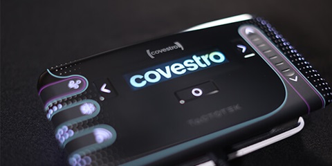 A black electronic device with several buttons and a display that shows a bright Covestro lettering