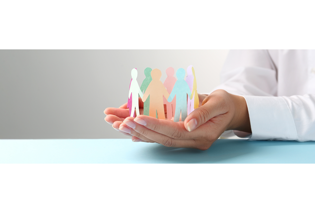 A woman's hands cupped together holding a circle of paper dolls holding hands