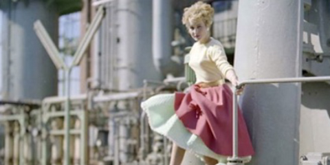 Fashionably dressed woman in a white and red dress in the middle of an industrial area.