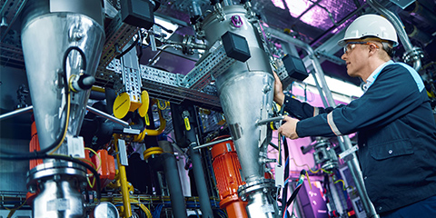 Employee in protective clothing operates a complex machine.