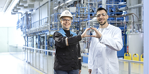 A factory worker and a laboratory worker form a circle with their hands.