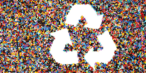 Illustration of a close-up of colored granules with a white recycling logo above.
