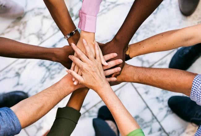 Group of people lined up in a circle and put their hands on top of each other.